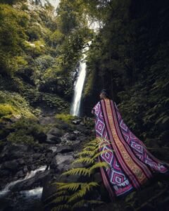 Pengunjung berfoto dengan latar belakang air terjun